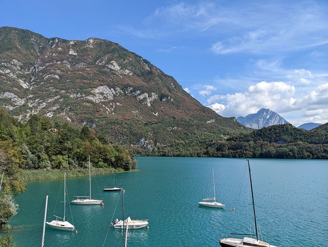Northern Italien mountains with vivid turquoise lake and small boats.